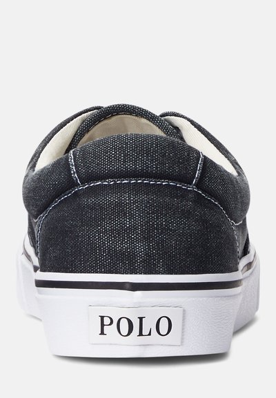 Μαύρα τζην slip-on παπούτσια με άσπρη σόλα, που διαθέτουν αντίθετη άσπρη ραφή και ετικέτα λογότυπου στη φτέρνα. Λείος υφασμάτινος τύπος, στρογγυλεμένο σχήμα.