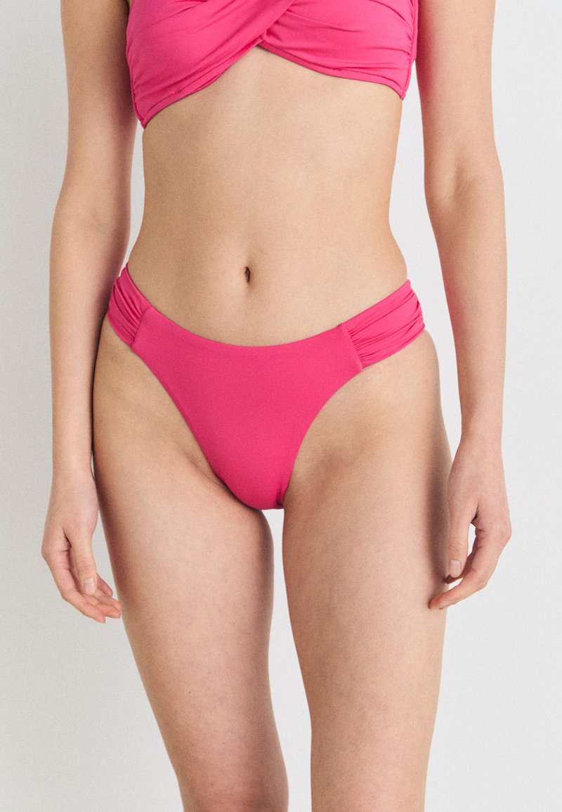 Rosa bikini med en tvinnad bandeau-topp och högskurna trosor med rynkade sidodetaljer, tillverkad av mjukt, elastiskt tyg.