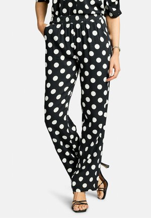 Čierne nohavice s bodkami majú elastický pás, bočné vrecká a voľný strih, pričom biele bodky sú rovnomerne rozmiestnené po celej látke.