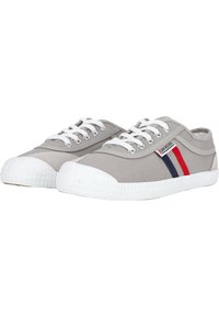 Grijze canvas sneakers met witte rubberen zolen, voorzien van witte veters en rode en blauwe zijkanten. Rond toelopende neus en laag uitgesneden ontwerp.