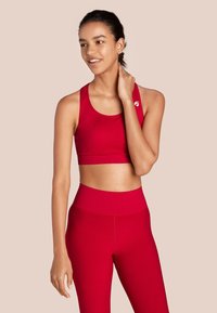 Rode sportbh met brede bandjes en een aansluitend ontwerp, gecombineerd met hoge rode leggings. Gladde textuur en minimale logo-details.