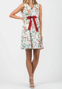 Floral dress in white with green and pink patterns, featuring a red fabric bow at the waist and a V-neckline. Lightweight fabric, sleeveless design.