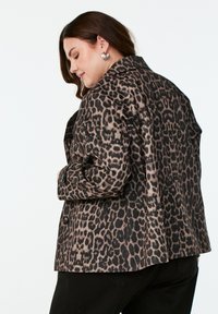 Veste en imprimé léopard avec un col, bénéficiant d'un tissu texturé, de deux boutons et d'une coupe décontractée. Vue arrière montrant le motif et le style.