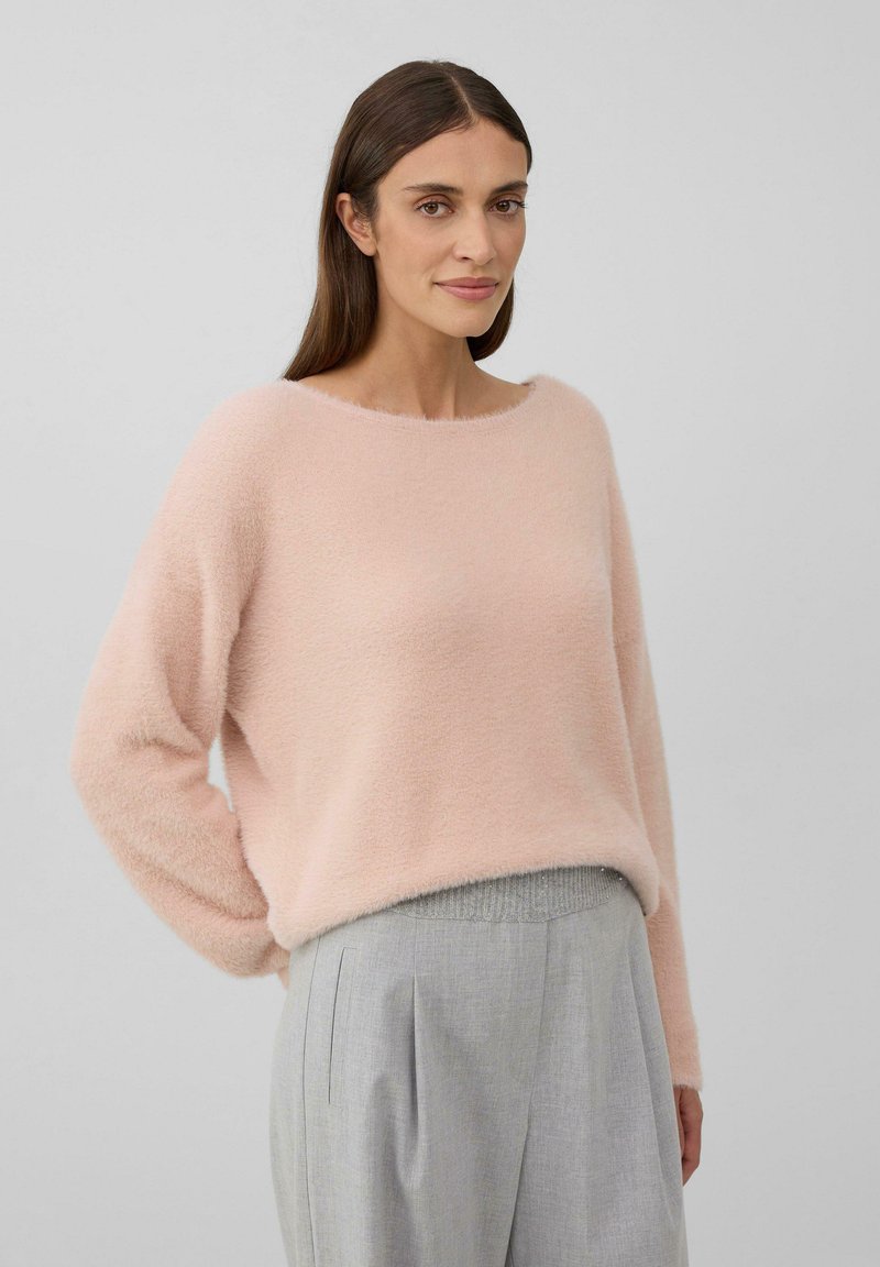 Pull en maille rose clair et moelleux, avec un décolleté large et des manches longues, associé à un pantalon cintré gris clair avec un design plissé.