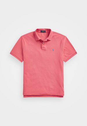 Koralo-różowa koszulka polo z krótkim rękawem, kołnierzykiem, plisą na dwa guziki oraz małym niebieskim haftowanym logo na lewej piersi.