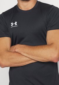 Zwart sport T-shirt met korte mouwen, gemaakt van gladde, vochtafvoerende stof, met een wit Under Armour-logo op de borst.