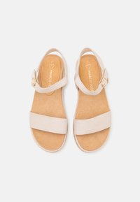 Beige skinnsandaler med to brede remmer og justerbar ankelrem, med en gullspenne og en brun polstret fotseng.