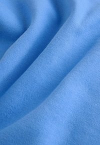 Svetlo modra tkanina z mehko, gladko teksturo, fino pletena, pada v gube, prikazuje svojo prilagodljivost in enakomerno porazdelitev barve.