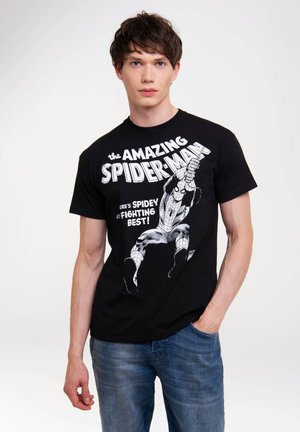 Black t-shirt featuring a Spider-Man graphic in white, depicting an action pose with bold lettering. Paired with blue denim jeans.