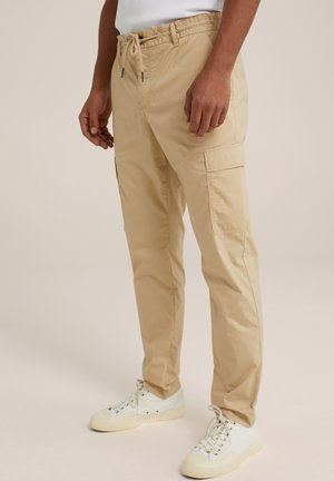 Pantaloni cargo bej cu talie elastică și șnur, dotati cu buzunare laterale și o textură netedă. Asortați cu adidași albi.