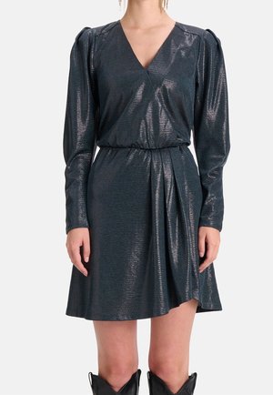 Vestido oscilante de un verde azulado brillante con mangas largas, escote en V profundo y cintura elástica. El detalle de tela fruncida en la falda añade dimensión.