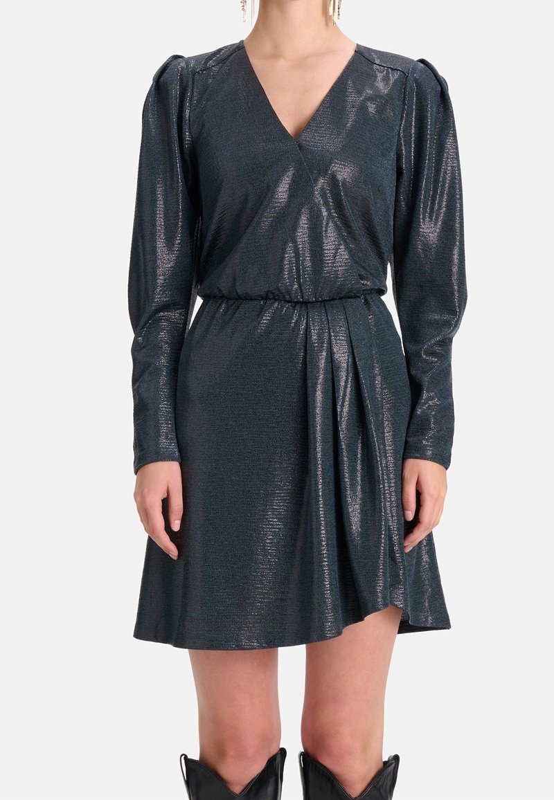 Lśniąca sukienka w ciemnym odcieniu teal z długimi rękawami, głębokim dekoltem w serek i elastycznym pasem. Marszczony detal w materiał na spódnicy dodaje wymiaru.