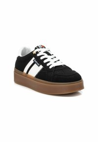 Zapatillas de ante negro con rayas blancas, punta redonda, suela gruesa de goma y cordones blancos; detalle del logo en la lengüeta.