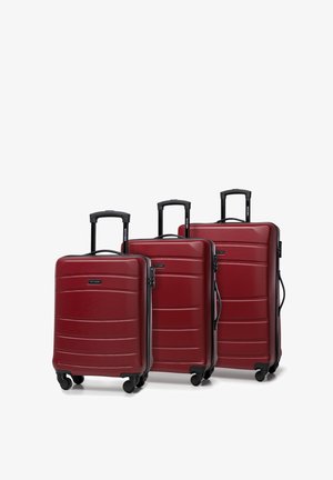 Drie rode harde koffers van verschillende formaten, met een gestructureerde afwerking, zwarte handvatten en soepel rollende wielen.