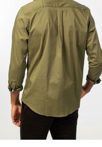 Olivgrön långärmad skjorta med rundad nederkant, knäppbara manschetter och veckdetalj på baksidan, tillverkad av ett mjukt och lätt material.