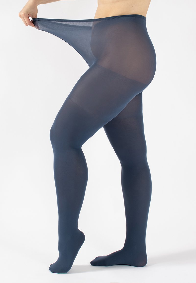Collant trasparente blu navy con una superficie liscia, caratterizzato da una vita alta e un design con piedini, mentre viene tirato su su una gamba su sfondo bianco.