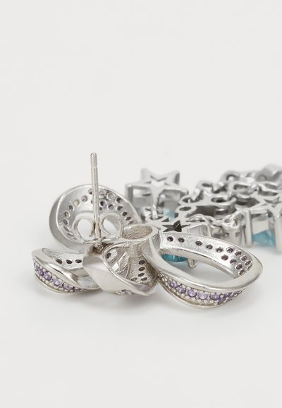 Silver earrings featuring a twisted design with purple gemstones, an intricate texture, and a post backing. Star-shaped accents in the background.