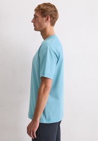 Jasnoniebieska bawełniana koszulka z krótkim rękawem, okrągłym dekoltem i prostym krojem. Bez widocznych wzorów ani grafik.