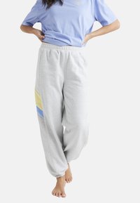 Lys grå sweatpants med elastisk talje og manchetter. Har gule og blå sidelæg. Fremstillet af blødt, tekstureret bomuldsblandingsstof.