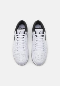 Białe buty do koszykówki z czarnymi akcentami, perforowanym noskiem, płaskimi sznurowadłami, wyściełanym kołnierzem oraz logo Jumpman na języku i bokach.