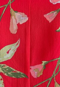 Tecido vermelho com um design floral, apresentando flores rosa claro e folhas verdes; superfície texturizada. Um padrão vibrante e detalhado.