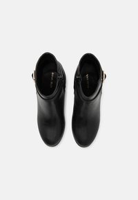 Botines de cuero negro con textura suave, que cuentan con una cremallera lateral y un acento metálico en el tobillo para un toque adicional.