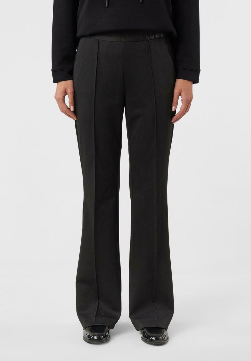 Czarne spodnie z rozszerzanymi nogawkami o gładkiej fakturze, z przodu z zakładkami i elastycznym paskiem w talii. Subtelne logo na pasku.