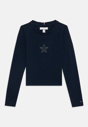 Chemise bleu marine à manches longues avec un col rond et un petit motif étoile en points au centre de la poitrine.