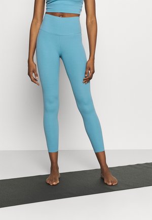 Leggings actifs bleu clair avec une taille haute, fabriqués en tissu lisse et extensible, se rétrécissant jusqu'aux chevilles. Design simple, uni.