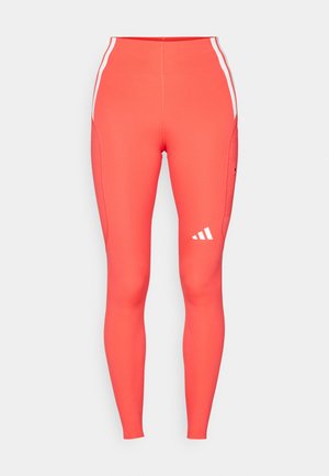 High-rise, fitted leggings in bright coral with white side stripes and a small white logo on the left leg. Smooth, stretchy fabric.