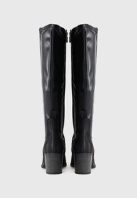 Tall black leather boots featuring a smooth finish, stacked heels, and zipper closures at the back, with textured accents on sides.