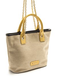 Bolsa tote de lona beige con asas de cuero amarillo y ribetes negros, con detalles de cadena dorada y una etiqueta con el logo en el frente.