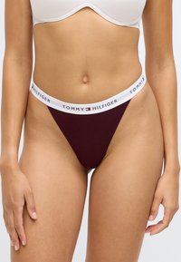 Burgunderfarget thong med hvit elastisk linning med "TOMMY HILFIGER"-logo, laget av myk tekstil for komfort.