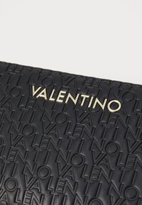Black embossed leather clutch with raised “VALENTINO” logo in gold hardware, rectangular shape, featuring a textured surface with repeating pattern.