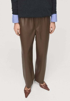 Bruine nepleer wijde broek met een elastische tailleband en koord, gecombineerd met een donkere trui en licht gestreepte manchetten.