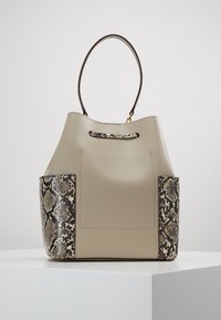 Hinkväska i ljusbeige läder med ormskinsmönstrade sidodetaljer, med en böjd handtag och en central slot upptill.