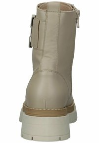 Botín de cuero beige hasta el tobillo con una textura suave, que presenta un zipper lateral y una suela blanca gruesa. Los detalles de costura añaden un toque especial.