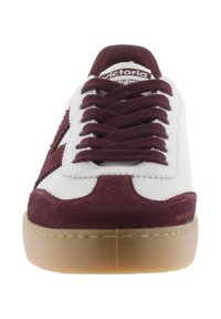 Vita sneakers med burgundy mockadetaljer, snörning framtill, vadderad krage och sula i gummirubber. Har en logotyp på plösen.