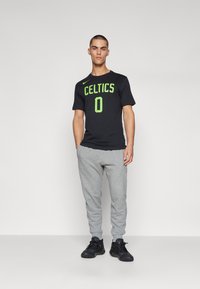 Must värvi spordit-särk, millel on neoonroheline "CELTICS" kiri ja number "0", koos hallide dressipükste ja mustade tossudega.