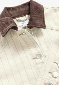 Beige jas met smalle strepen,bruine corduroy kraag, knoopsluitingen en klepzakken. Gemaakt van katoen met een gestructureerde afwerking.