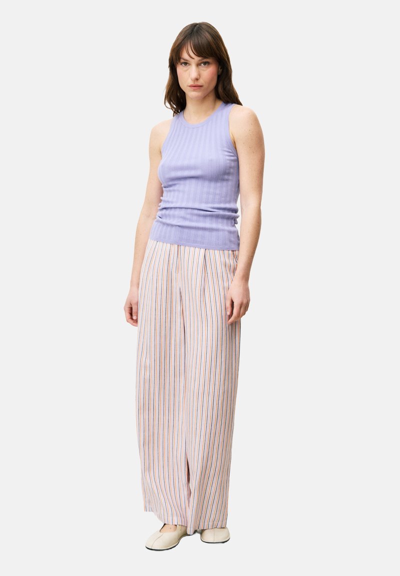 Lichtpaarse geribde tanktop gecombineerd met brede, gestreepte broek in oranje en blauwe lijnen. Zachte textuur met een casual pasvorm.