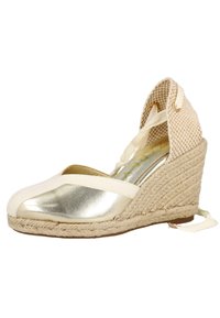 Cuña de esparto en color beige con una puntera dorada brillante, parte superior de tejido trenzado y lazos de cinta. Presenta un tacón de cuña cubierto de yute para añadir textura.