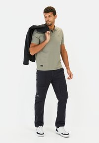 Lys olivengrøn polo t-shirt med korte ærmer, parret med mørkeblå cargo bukser med flere lommer og hvide sneakers.
