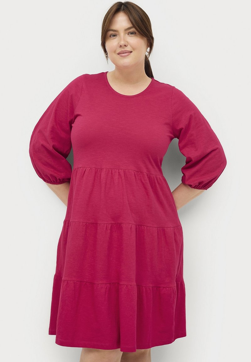 Fuchsie Baumwollkleid mit dreiviertel Puffärmeln, das ein gestuftes Rockdesign und einen runden Ausschnitt aufweist. Glatte Textur, lockerer Schnitt.