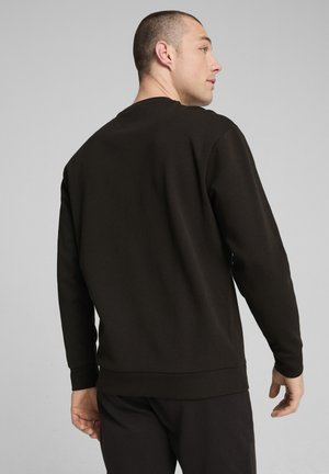 Felpa nera con collo rotondo, maniche lunghe e una trama a maglia stretta. Il retro presenta una finitura liscia con orlo a coste.