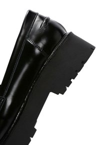 Stivale alla caviglia in pelle nera con finitura lucida, punta rotonda e suola spessa caratterizzata da un design a scanalature.
