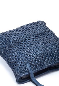 Bolso de mano azul tejido que presenta una superficie texturizada, acentos de cuero y un cierre de cremallera. Forma rectangular compacta con un diseño estampado.
