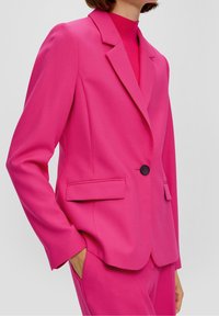 Jasnoróżowa, dopasowana marynarka z wyciętymi klapami, zapięciem na guziki z przodu i bocznymi kieszeniami, wykonana z gładkiej tkaniny.
