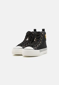 Sorte høytoppsneakers laget av lerret, med hvite gummitopper, gullfargede maljer og en teksturert hvit plattformsåle med striper.