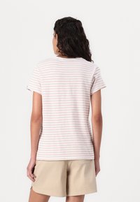 Stripet kortermet t-skjorte i myk stoff, med lyserosa og hvite striper, rund halslinning, og en avslappet passform. Sammen med beige shorts.